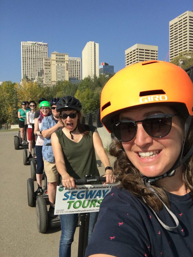 Emma taking a selfie with the Full Stacks team riding Segways in a line in downtown Edmonton.